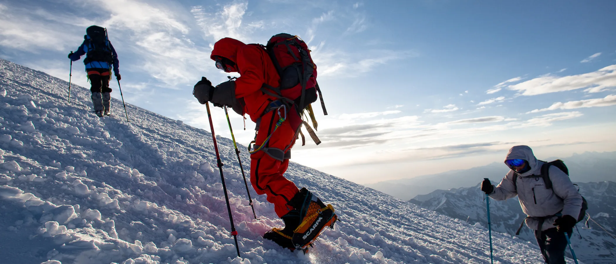Mountaineers climbing a snow ridge at dawn